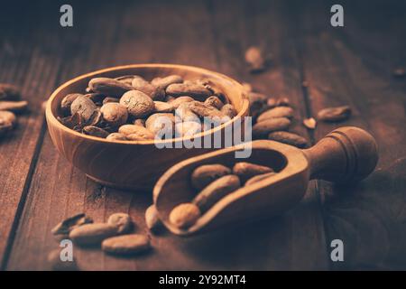 Fèves de cacao bio dans un bol en bois sur fond en bois Banque D'Images