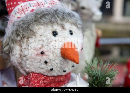 Un affichage de Noël extrêmement mignon en forme de bonhomme de neige avec une écharpe de note de carotte rouge et un chapeau laineux sur le décor de décorations de Noël Banque D'Images