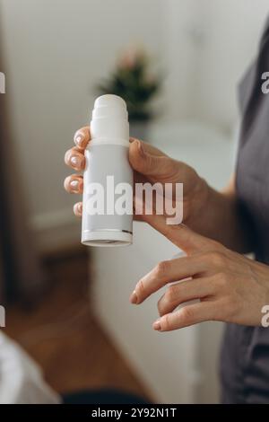 La cosmétologue tient un pot de crème pour le visage pendant une séance de soins de la peau. Crème maquette blanche. Photo de haute qualité Banque D'Images