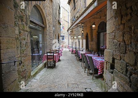 Sarlat, France 22 juillet 2024 : tables et chaises disposées prêtes à accueillir les clients dans une petite rue de la vieille ville de Sarlat en Dordogne Banque D'Images