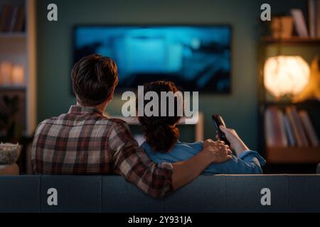 Famille heureuse regardant la télévision, films le soir à la maison. Couple passant du temps ensemble. Banque D'Images