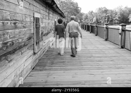 Couple caucasien, 55 à 60 ans, marchant le long du trottoir de River Walk Park dans le quartier historique des entrepôts de Conway, Caroline du Sud, États-Unis. Banque D'Images