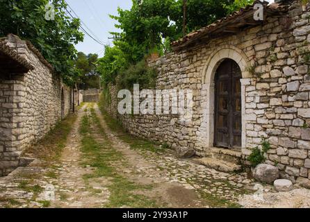 Une ruelle pavée herbeuse dans le quartier résidentiel historique du quartier du château, Kalaja, de Berat dans le sud de l'Albanie. Murs en pierre traditionnels Banque D'Images