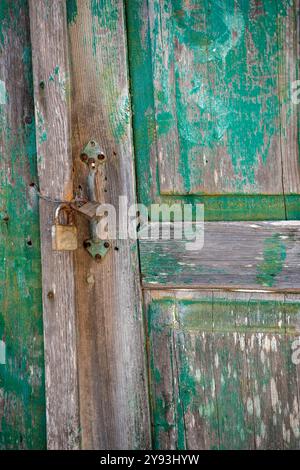 abstrait de la porte en détresse peinte en vert battu par les intempéries avec vieux loquet rouillé et serrure Banque D'Images