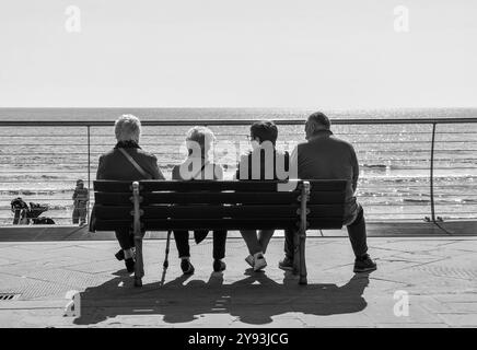 Photo noir et blanc. Trois dames âgées et un gentleman se reposant sur un banc sur la promenade de la station balnéaire, Alassio, Savona, Ligurie, Italie Banque D'Images