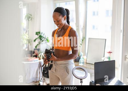 Femme souriante en vêtements de sport chez elle Banque D'Images