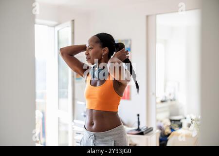 Femme souriante en vêtements de sport chez elle Banque D'Images