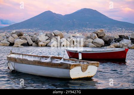 Vue pittoresque du Vésuve au coucher du soleil, Naples, Italie. Deux bateaux traditionnels au premier plan, capturant l'essence du paysage de Naples Banque D'Images