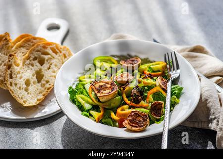 Une délicieuse salade chaude de laitue croustillante, des rondelles d'oignon sautées et des tranches de mini aubergines blanches carbonisées. La salade est garnie de cloche verte peppe Banque D'Images