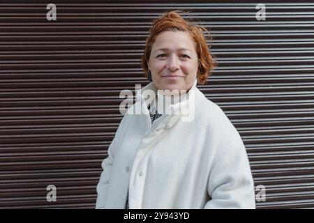 Portrait chaleureux et naturel d'une femme d'âge moyen aux cheveux courts et gingembre, enfilant un élégant manteau blanc sur une chemise à motifs, posant devant une côte Banque D'Images