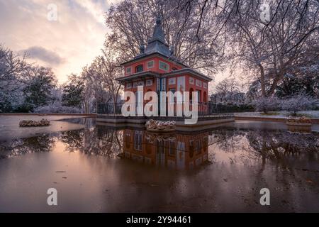 Une vue pittoresque d'un bâtiment traditionnel de Madrid, la Casita del Pescador dans le parc Buen Retiro couvert de neige, reflété dans une flaque d'eau à proximité Banque D'Images