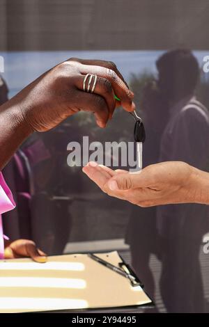 Gros plan méconnaissable d'une agent immobilier noire remettant les clés de la maison à un client anonyme, signifiant l'achèvement d'un hom Banque D'Images