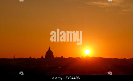 Cette superbe photographie capture un coucher de soleil époustouflant sur Rome, mettant en valeur la silhouette de la basilique Saint-Pierre dans un ciel orange vif Banque D'Images