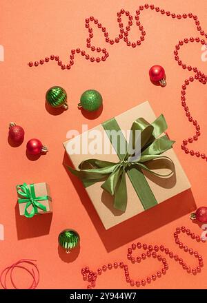Une vue aérienne de cadeaux de Noël enveloppés dans du papier écologique orné de rubans de satin vert, entourés de boules rouges et vertes et de chatoyants Banque D'Images