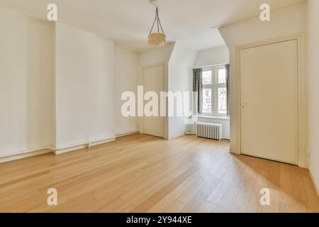 Une vaste salle vide bien éclairée avec un parquet en bois franc poli, de grandes fenêtres et des détails vintage classiques. Banque D'Images