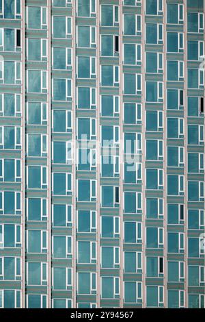 Vue rapprochée de la façade en verre symétrique d'un gratte-ciel contemporain à New York. Les motifs répétitifs des fenêtres créent une arche étonnante Banque D'Images