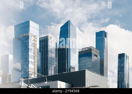 Une vue des gratte-ciels de verre modernes, y compris les bâtiments hauts et frappants, sous un ciel partiellement nuageux à New York. L'image capture la grandeur Banque D'Images