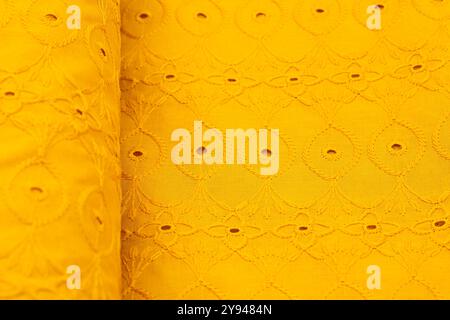 Tissu jaune vif avec motif de broderie circulaire complexe, parfait pour les designs d'été et les projets textiles créatifs Banque D'Images