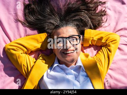 Belle femme d'affaires senior portant une tenue d'affaires décontractée se promenant dans le quartier des affaires de la ville - adulte d'entreprise mature allant travailler à Banque D'Images
