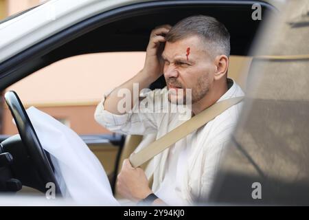 Homme blessé près d'un airbag ouvert dans une automobile après un accident de voiture Banque D'Images