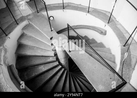 Un escalier à double hélice unique en spirale présente gracieusement son design complexe. Les marches en pierre et les balustrades créent une atmosphère accueillante dans l'espace intérieur. Banque D'Images