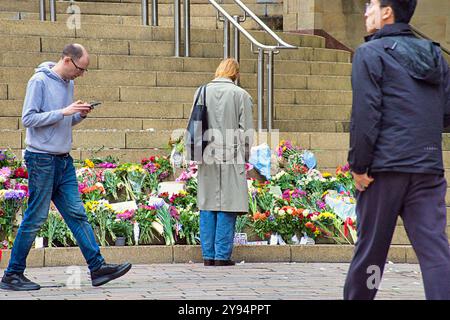 Glasgow, Écosse, Royaume-Uni. 8 octobre 2024. Météo au Royaume-Uni : sec alors que les gens passaient leur vie gouvernée par la météo dans le centre de la ville. L'hommage aux fleurs palestiniennes entre dans son troisième jour sur les marches de la salle de concert royale avec de nouvelles fleurs ajoutées. Crédit Gerard Ferry/Alamy Live News Banque D'Images