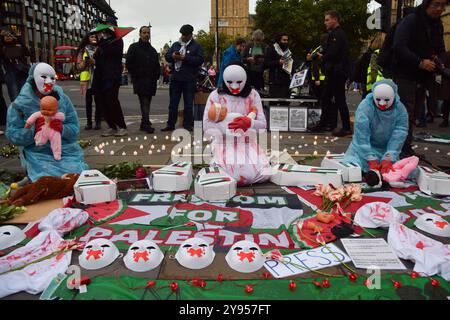 Londres, Angleterre, Royaume-Uni. 8 octobre 2024. Les manifestants portant des masques tiennent des poupées représentant des enfants blessés et mourants alors que les partisans de la Palestine organisent une veillée sur la place du Parlement pour plus de 41 000 personnes tuées à Gaza à l'occasion du premier anniversaire de la guerre Israël-Hamas, qui a commencé lorsque le Hamas a tué et enlevé des Israéliens au festival de musique Nova le 7 octobre 2023. (Crédit image : © Vuk Valcic/ZUMA Press Wire) USAGE ÉDITORIAL SEULEMENT! Non destiné à UN USAGE commercial ! Banque D'Images