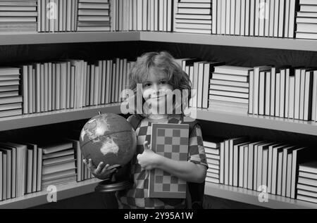 Garçon d'école avec le monde et les échecs, l'enfance. Concept d'école et d'éducation. Portrait d'un enfant garçon scolaire mignon. Retour à l'école. Banque D'Images