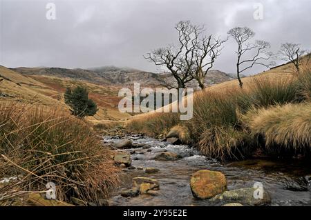 Rivière Kinder regardant vers Kinder Scout avec une quantité de neige et quelques nuages bas sur les sommets des collines. Banque D'Images