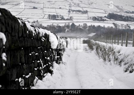 Une journée très froide à Calderdale avec de la neige au sol et spindrift dans les airs. Murs de pierre et champs enneigés. Banque D'Images