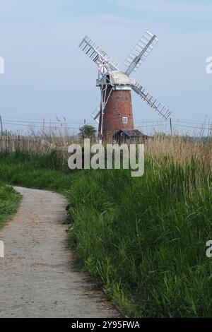 Une vue de Horsey Windpump un moulin de travail restauré, avec un chemin, de l'herbe et des roseaux au premier plan. Norfolk, Angleterre, Royaume-Uni Banque D'Images