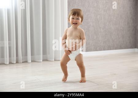 Mignon petit enfant dans la couche à la maison Banque D'Images