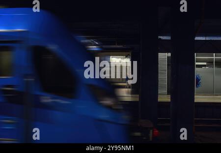 Varsovie, Pologne - 27 septembre 2024 : un train bleu se déplace rapidement dans une station de métro, capturé dans un mouvement flou contre une plate-forme faiblement éclairée Banque D'Images