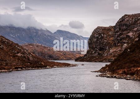 Des collines escarpées s'élèvent des rives du Loch na Tull près de Riconich dans les Highlands de l'extrême nord de l'Écosse, avec la montagne Foinaven en arrière-plan. Banque D'Images