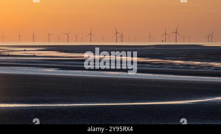 Le soleil se couche derrière les éoliennes dans la mer d'Irlande vu de la péninsule de Wirral en Angleterre. Banque D'Images