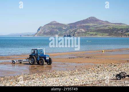 Un tracteur est garé sur la plage de Morfa Nefyn sur la péninsule de Llŷn au nord du pays de Galles, avec la colline Yr Eifl qui monte au loin. Banque D'Images