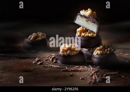 Pralines de massepain avec enrobage de chocolat noir et garniture de noix, entières et coupées en deux, empilées sur des planches rustiques de bois foncé, bonbons de vacances, spa de copie Banque D'Images