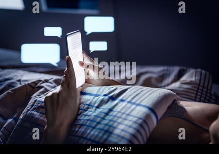 Téléphone envoyer des SMS dans le lit la nuit avant de dormir. Femme avec smartphone. DM, message direct. Escroquerie SMS. Durée de l'écran. Discutez avec votre téléphone portable. Secret ou commérage. Banque D'Images