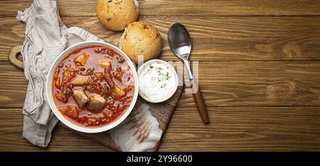 Borscht ukrainien, soupe de betterave rouge avec de la viande, dans un bol blanc avec de la crème sure, petits pains à l'ail Pampushka et tranches de salo sur fond de pierre rustique. TRADI Banque D'Images