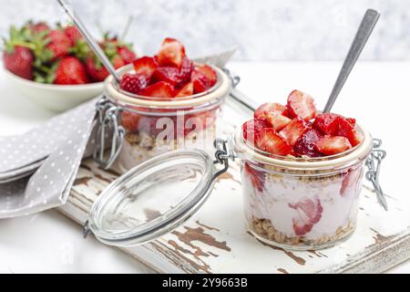 Parfait avec des fraises fraîches, yaourt et granola Crunchy en verre transparent Mason jarres sur fond en bois rustique blanc de angle View, Santé Banque D'Images