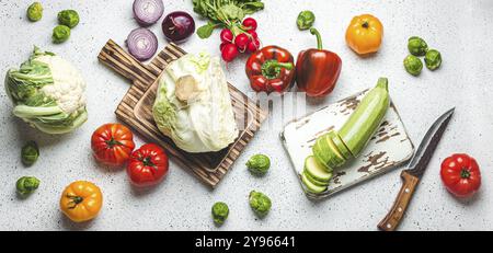 Légumes frais divers avec planches à découper en bois et couteau sur table de cuisine blanche vue sur le dessus. Cuisine repas végétarien à partir d'ingrédients sains, régime Banque D'Images