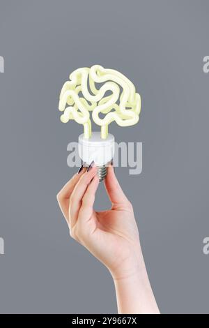 Tenir une lampe à économie d'énergie avec un cerveau Banque D'Images