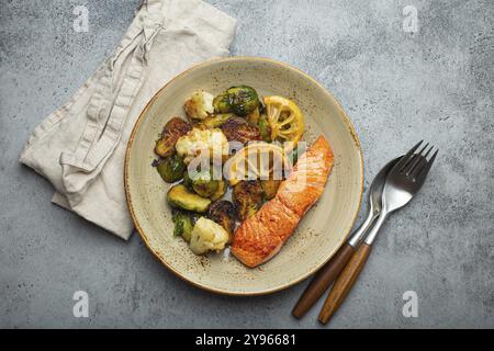 Délicieux filet de saumon avec choux de Bruxelles grillés sur l'assiette, fond de pierre rustique vue de dessus. Dîner sain avec poissons et légumes grillés, bal Banque D'Images