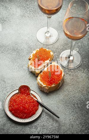 Petite assiette en métal avec caviar de saumon rouge, deux toasts de caviar canape, deux verres de champagne vue de dessus sur fond de béton gris, épicerie de luxe festive Banque D'Images