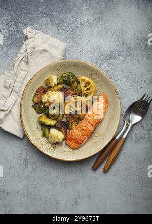 Délicieux filet de saumon avec choux de Bruxelles grillés sur l'assiette, fond de pierre rustique vue de dessus. Dîner sain avec poissons et légumes grillés, bal Banque D'Images