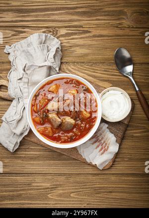 Borscht ukrainien, soupe de betterave rouge avec de la viande, dans un bol blanc avec de la crème sure et des tranches de salo sur fond en bois rustique vue de dessus. Traditionnel auten Banque D'Images