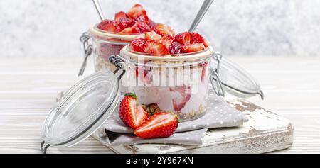 Parfait avec des fraises fraîches, yaourt et granola Crunchy en verre transparent Mason jarres sur fond en bois rustique blanc de angle View, Santé Banque D'Images