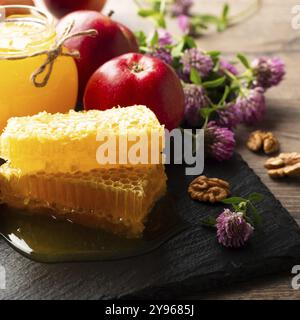 Pot Mason avec miel, nid d'abeille, pommes rouges et noix sur la table de cuisine, photographie alimentaire, photographie alimentaire Banque D'Images