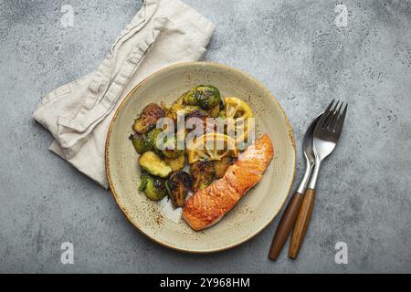 Délicieux filet de saumon avec choux de Bruxelles grillés sur l'assiette, fond de pierre rustique vue de dessus. Dîner sain avec poissons et légumes grillés, bal Banque D'Images