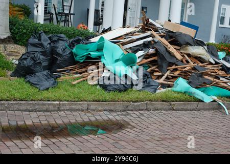 Gros tas de déchets, meubles, articles ménagers empilés sur le côté d'une bordure de rue en briques. Après une tempête endommageant l'inondation d'une onde de tempête d'eau. Attendez Banque D'Images